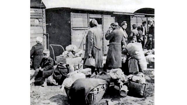 Lidé s osobními věcmi čekají na odsun z Československa. Archiv Jindřicha Nového.